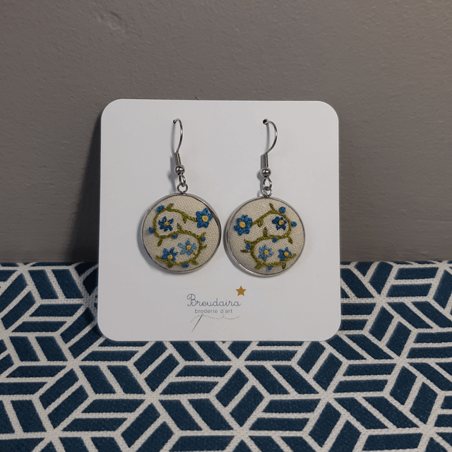 Boucles d'oreilles fleurs bleues fond blanc