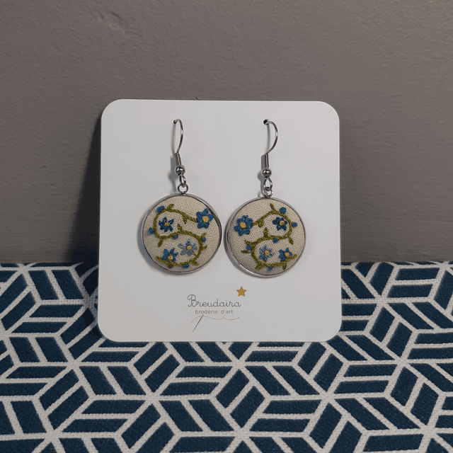 Boucles d&#039;oreilles fleurs bleues fond blanc